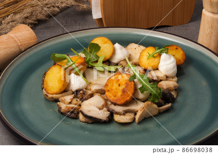 fried porcini mushrooms with new potatoes garnished with arugula fried porcini mushrooms with new potatoes garnished with arugula 86698038