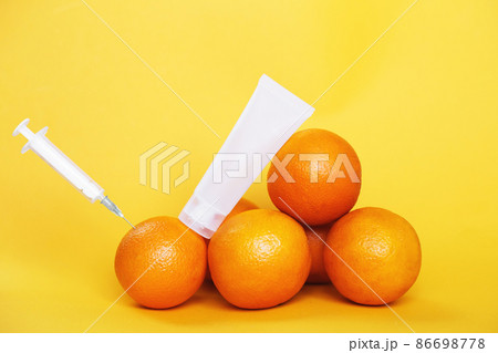 orange fruits with syringe extracting liquid with vitamin C and empty cream tube. natural anti aging cosmetics concept orange fruits with syringe extracting liquid with vitamin C and empty cream tube. natural anti aging cosmetics concept 86698778
