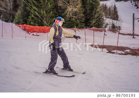 Woman learning to ski. Young woman skiing on a snowy road in the mountains 86700193