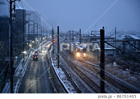 雪の夕暮れ鉄道風景 近づきつつある電車のヘッドライト 道路を走る自動車のヘッドライト 光が雪を照らす 雪の夕暮れ鉄道風景 近づきつつある電車のヘッドライト 道路を走る自動車のヘッドライト 光が雪を照らす 86701405