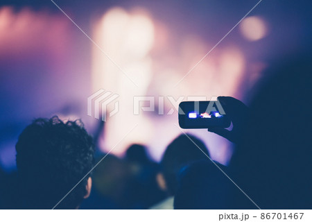Fan taking photo of concert with a mobile phone 86701467