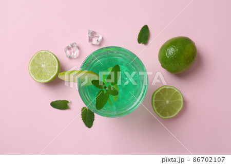 Glass of lime cocktail and ingredients on pink background Glass of lime cocktail and ingredients on pink background 86702107