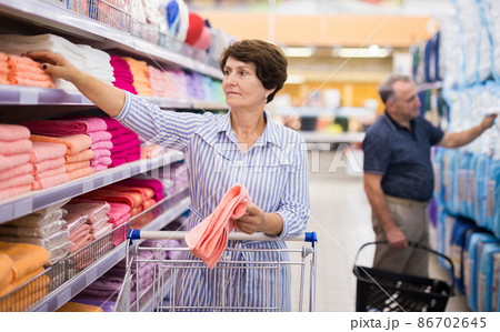 elderly retired senora buying pink towels in linen section of supermarket elderly retired senora buying pink towels in linen section of supermarket 86702645