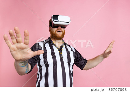 Comic portrait of sport referee wearing field judge uniform in VR headset isolated on pink studio background. Concept of sport, rules, competitions, rights, ad, sales. Comic portrait of sport referee wearing field judge uniform in VR headset isolated on pink studio background. Concept of sport, rules, competitions, rights, ad, sales. 86707098