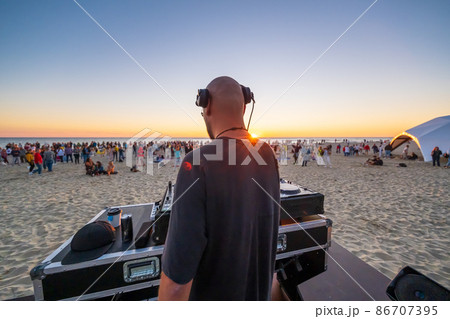 DJ playing music on beach during sunset DJ playing music on beach during sunset 86707395