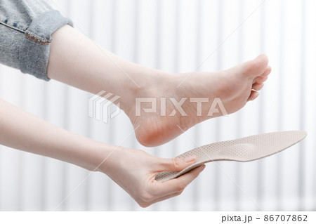 Doctor holding an insole while sitting at a table. Orthopedist tests the medical device. Orthopedic insoles. Foot care. Flat Feet Correction. Treatment and prevention of flat feet and foot diseases. 86707862