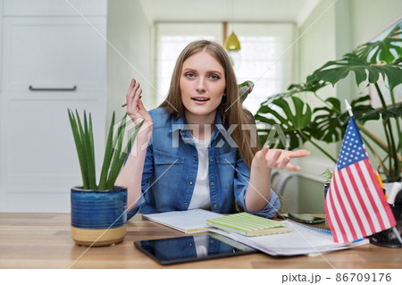 Young female student looking at the camera, USA flag on the table. Young female student looking at the camera, USA flag on the table. 86709176