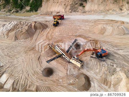 Arial view of the sand open-pit mining with heavy mining machinery. Mobile stone jaw crusher machine 86709926