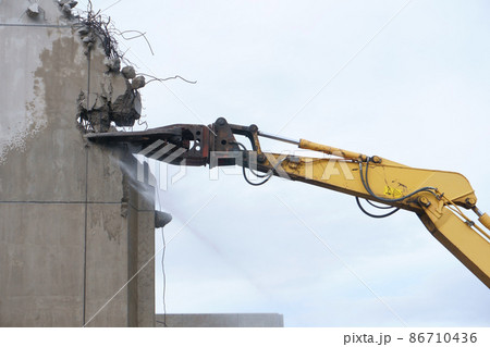 老朽化した公共建造物の解体作業をする重機 86710436