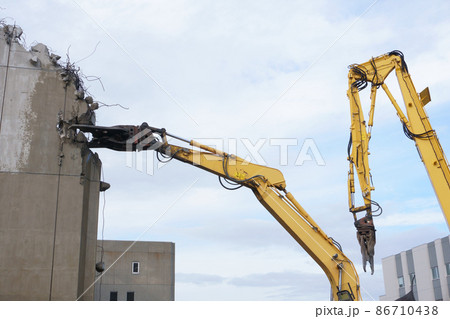 老朽化した公共建造物の解体作業をする重機 86710438