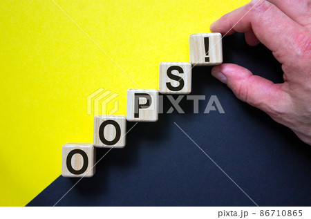 Wood cubes with word 'oops' on paper yellow and black background, copy space. Male hand. Business concept success process. Wood cubes with word 'oops' on paper yellow and black background, copy space. Male hand. Business concept success process. 86710865