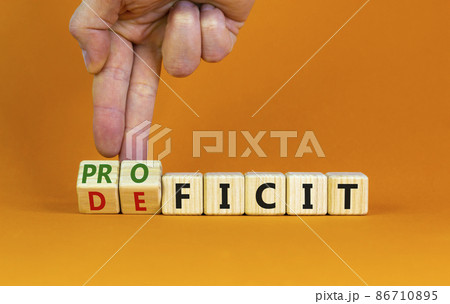 Proficit or deficit symbol. Businessman turns cubes, changes the word deficit to proficit. Beautiful orange table, orange background, copy space. Business, proficit or deficit concept. 86710895