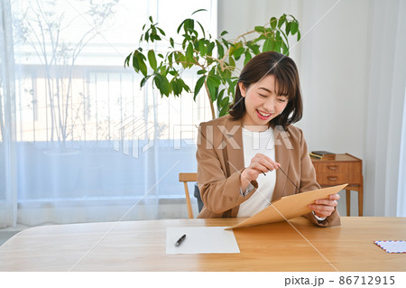 机で玉紐封筒を開ける女性 86712915