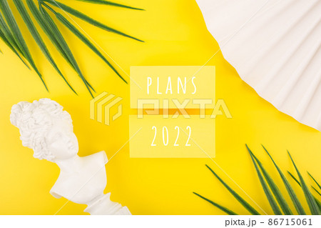 Creative trendy plans for 2022 concept. Text written on yellow tablets next to white gypsum woman figure, waver and palm leaves 86715061
