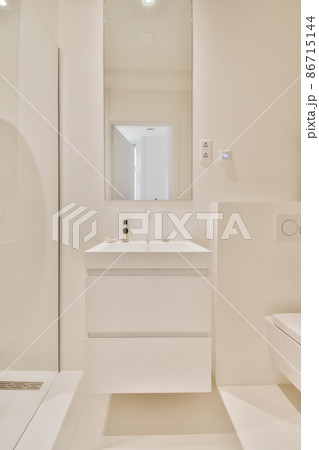Stylish white sink and mirror on the wall in a white modern bathroom Stylish white sink and mirror on the wall in a white modern bathroom 86715144