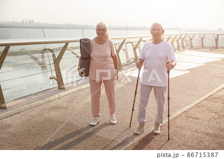 Sportive senior woman and man stand on footbridge at sunset light 86715387