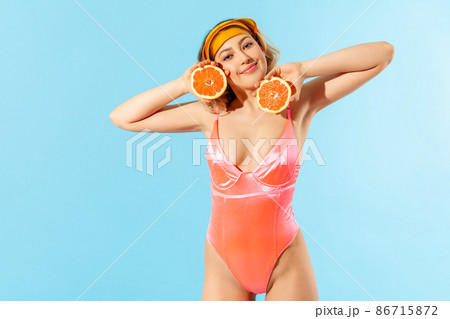 Portrait of charming happy woman in swimsuit holding fresh cut orange and looking at camera with smile. Concept of female beauty, natural cosmetic antioxidant, healthy nutrition. isolated 86715872