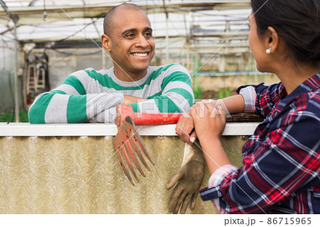 Hispanic male farmer talks to a female colleague, discussing interesting topics. Hispanic male farmer talks to a female colleague, discussing interesting topics. 86715965
