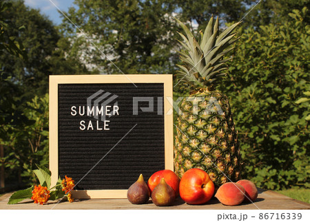 Fresh Pineapple outdoors with Apricots, Peaches and figs. sale sign garden in background Fresh Pineapple outdoors with Apricots, Peaches and figs. sale sign garden in background 86716339