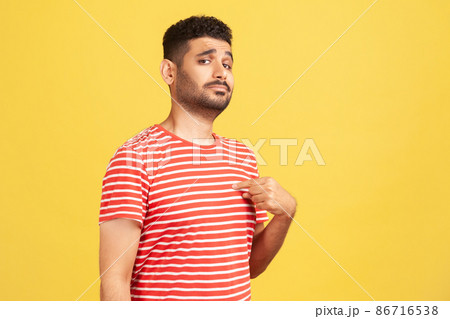Egocentric selfish man pointing finger at himself, looking with pride and arrogance, feeling self-important and famous. Indoor studio shot isolated on yellow background 86716538