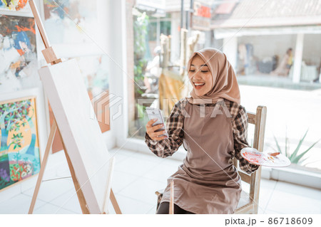 muslim female artist looking for inspiration from her mobile phone 86718609