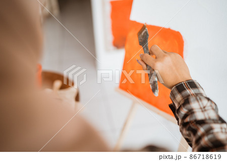 female artists hand holding a paint brush with color palette painting in studio 86718619
