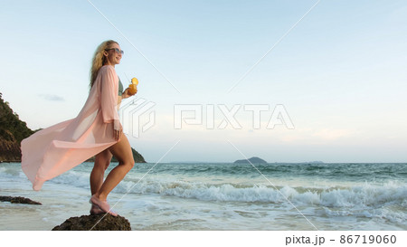 Woman stand on a reef rock stone in sea on sunset. Girl on beach 86719060