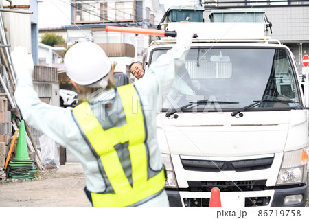 トラック（車両）を誘導する交通誘導員の男性 86719758