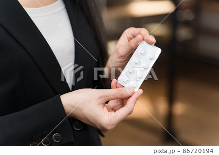 錠剤のPTP包装パッケージを手に持つスーツの女性　パーツカット 86720194