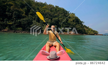 Man with sunglasses and hat rows pink plastic canoe along sea ag Man with sunglasses and hat rows pink plastic canoe along sea ag 86724642