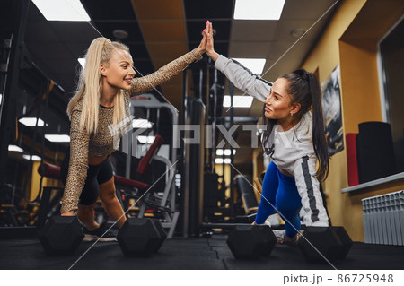 Sporty women giving high five to each other while working out together at gym. 86725948