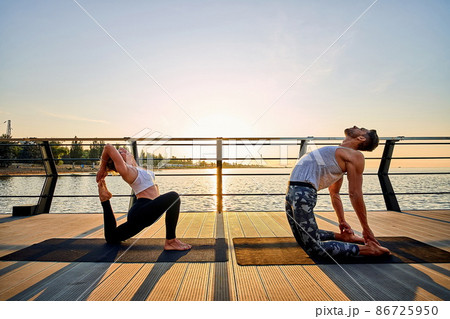 Couple practicing acrobatic yoga together on nature outdoors at sea. 86725950