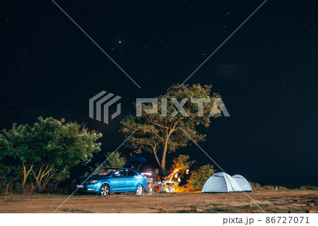 Group of five travellers rest on sea shore on evening sky background. 86727071