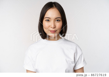 Close up portrait of young asian woman looking at camera, wearing t-shirt, smiling and looking happy, white background 86727619