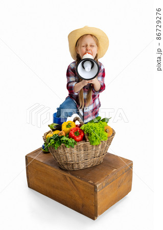 One cute little girl, emotive kid in image of farmer, gardener with large basket of vegetables isolated on white background. Concept of job, work, childhood, games 86729276