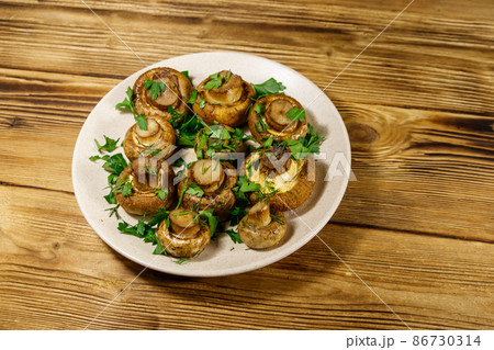 Baked mushrooms in plate on wooden table 86730314