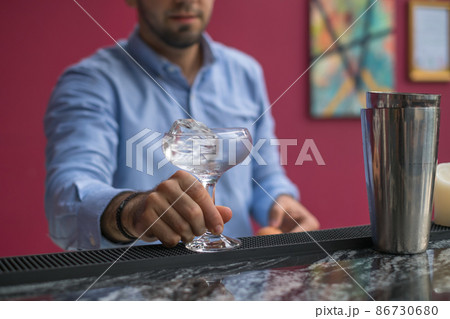 Bartender cools the glass with ice before making a cocktail. Close up photo, process, bar. High quality photo Bartender cools the glass with ice before making a cocktail. Close up photo, process, bar. High quality photo 86730680