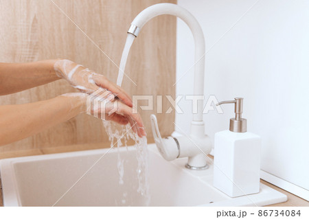 Washing hands under the flowing water tap. Washing hands rubbing with soap for corona virus prevention, hygiene to stop spreading corona virus in or public wash room. Hygiene concept hand detail. Washing hands under the flowing water tap. Washing hands rubbing with soap for corona virus prevention, hygiene to stop spreading corona virus in or public wash room. Hygiene concept hand detail. 86734084