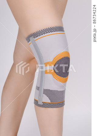 Knee Support Brace on leg isolated on white background. Elastic orthopedic orthosis. Anatomic braces for knee fixation, injuries and pain. Protective knee joint bandage sleeve. Trauma, rehabilitation. 86734224