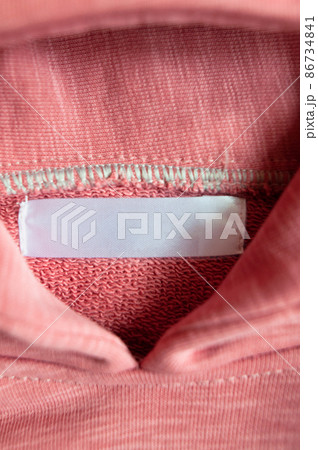 Closeup white blank clothing tag label on pink collar hoodie. Vertical photo. Selective focus. 86734841