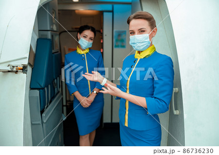 Flight attendants in medical masks inviting on board of aircraft 86736230