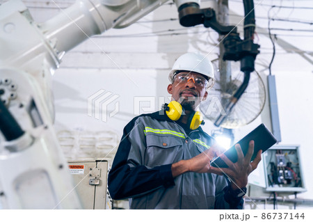 African American factory worker working with adept robotic arm 86737144