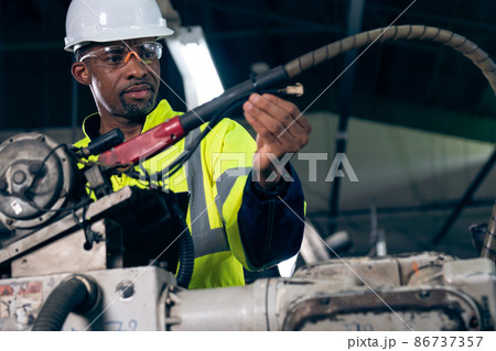 African American factory worker working with adept robotic arm 86737357