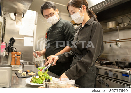 感染症対策のマスクをして料理する男女のスタッフ 86737640