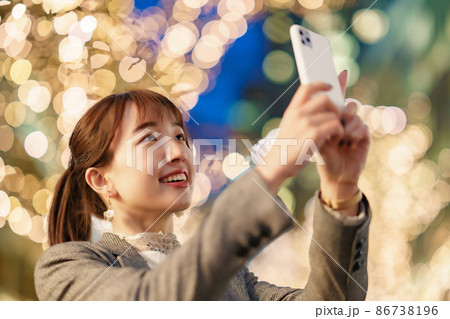 イルミネーションが輝く通りで写真を撮る女性 イルミネーションが輝く通りで写真を撮る女性 86738196