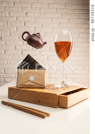 a tea table with tea and a wine glass in which Sheng Pu'er tea is poured to demonstrate the color 86738318