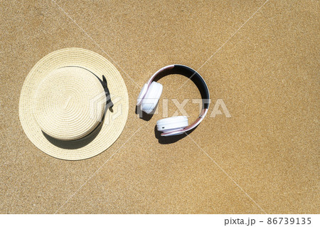 Summer straw hat, headphones  lying on sand of beach. Travel, holiday, summertime concept. Copy space. Top view. Flat lay 86739135