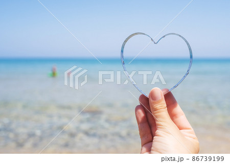 Sea view through shape of heart in the female hand of tropical beach. Valentines day. Holiday, vacation concept. Creative, background, copy space, travel, summer. 86739199