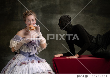 Young beautiful woman in image of medieval royal person in renaissance style dress and her page isolated on dark vintage background. 86739361