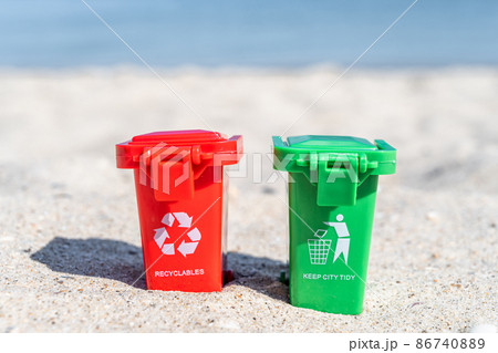 Different colored trash cans red and green with paper, plastic, glass and organic waste suitable for recycling on sandy beach. Segregate waste, sorting garbage Different colored trash cans red and green with paper, plastic, glass and organic waste suitable for recycling on sandy beach. Segregate waste, sorting garbage 86740889
